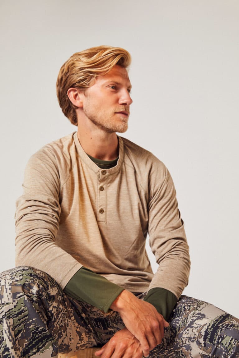 Beige lase layer garments by Spectre on a sitting blonde male model